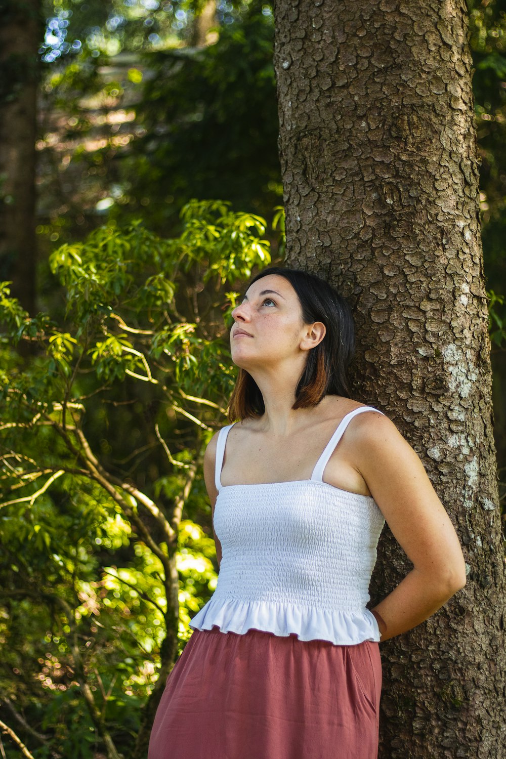 a woman leaning against a tree in a forest