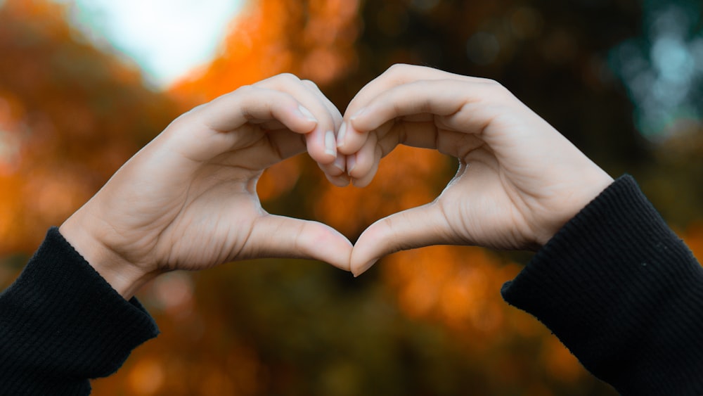 a person making a heart shape with their hands