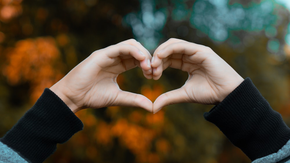 a person making a heart shape with their hands