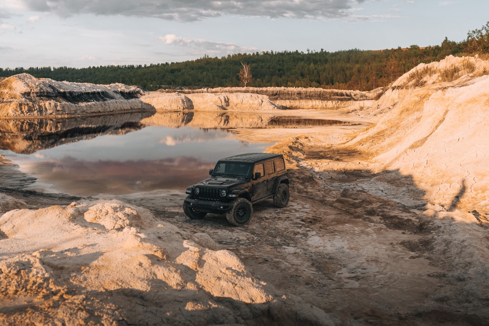 a jeep is parked on the edge of a lake