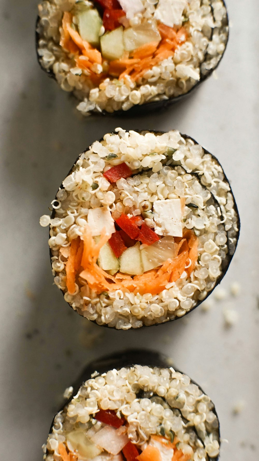 three sushi rolls with carrots, cucumbers, and other toppings