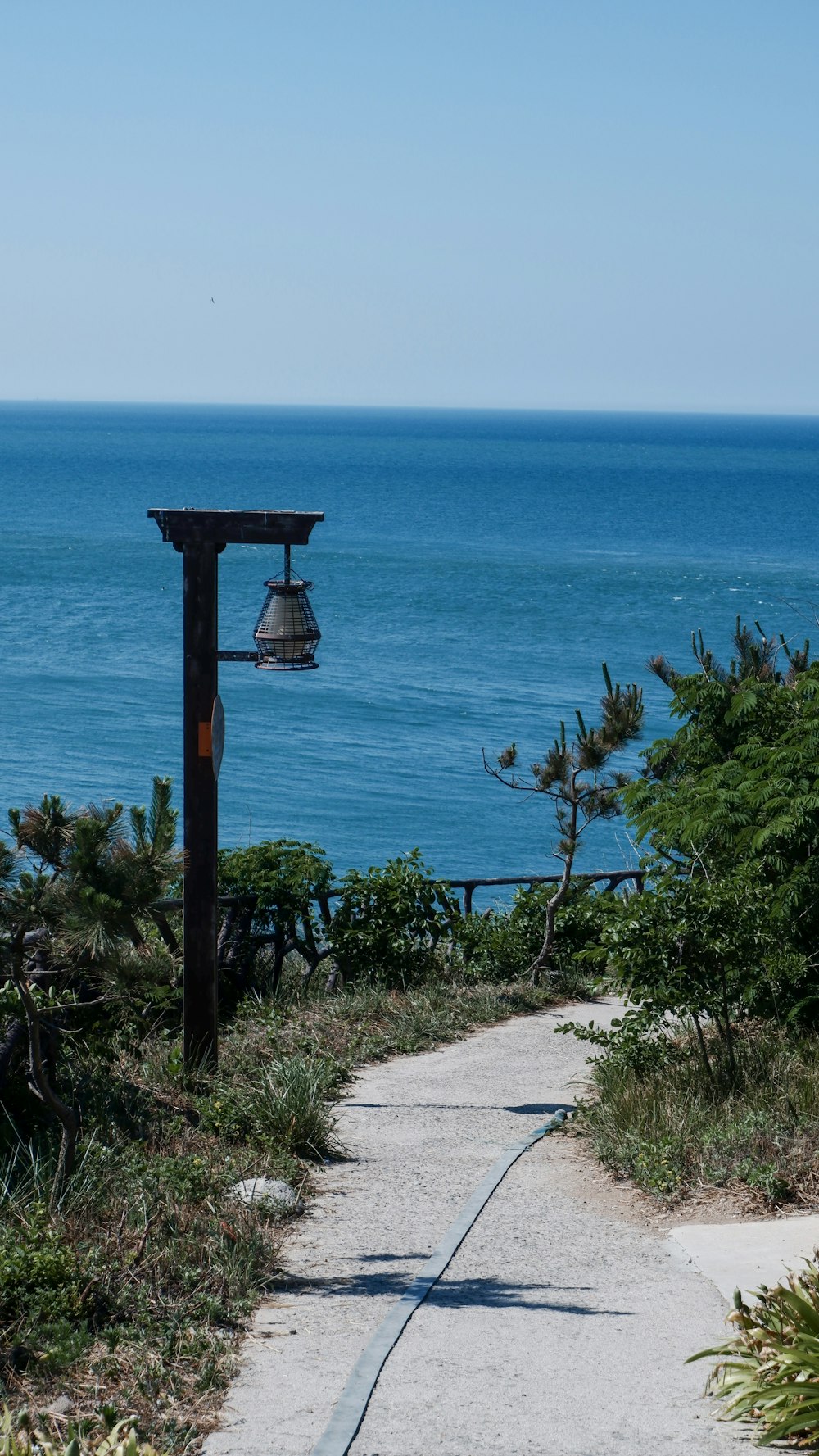 a path leading to the ocean with a bell on it