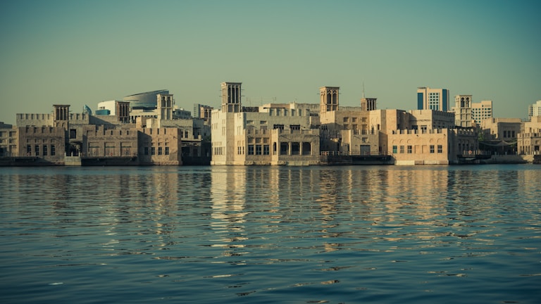 A serene boat ride along Dubai Creek with historic buildings in the background