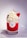A decorative candle in a glass holder designed to resemble a dessert with red wax at the bottom and white, whipped cream-like wax swirled on top. There is a small, red strawberry-shaped detail and a stick embedded in the cream. The candle is labeled 'Candle of Soul'.