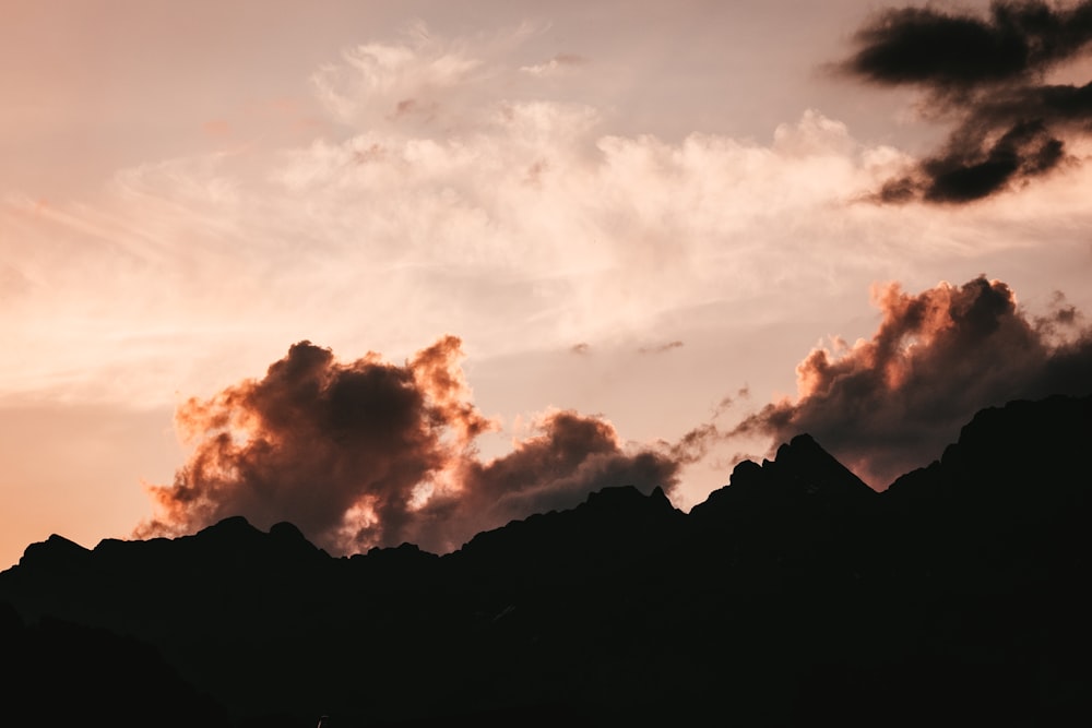 the silhouette of a mountain with clouds in the sky