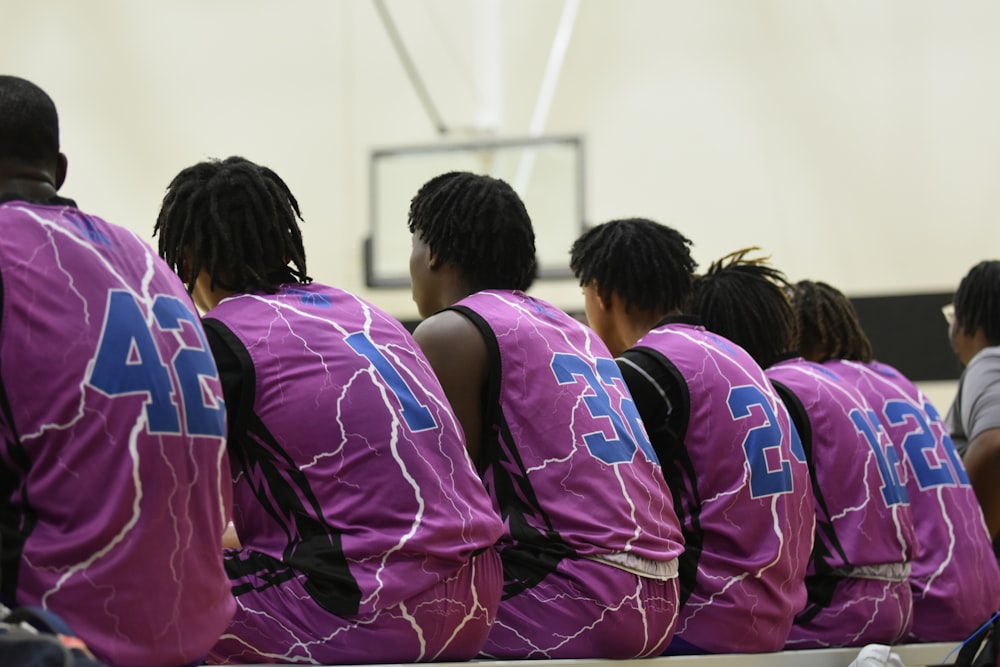 a group of young men sitting on top of a basketball court