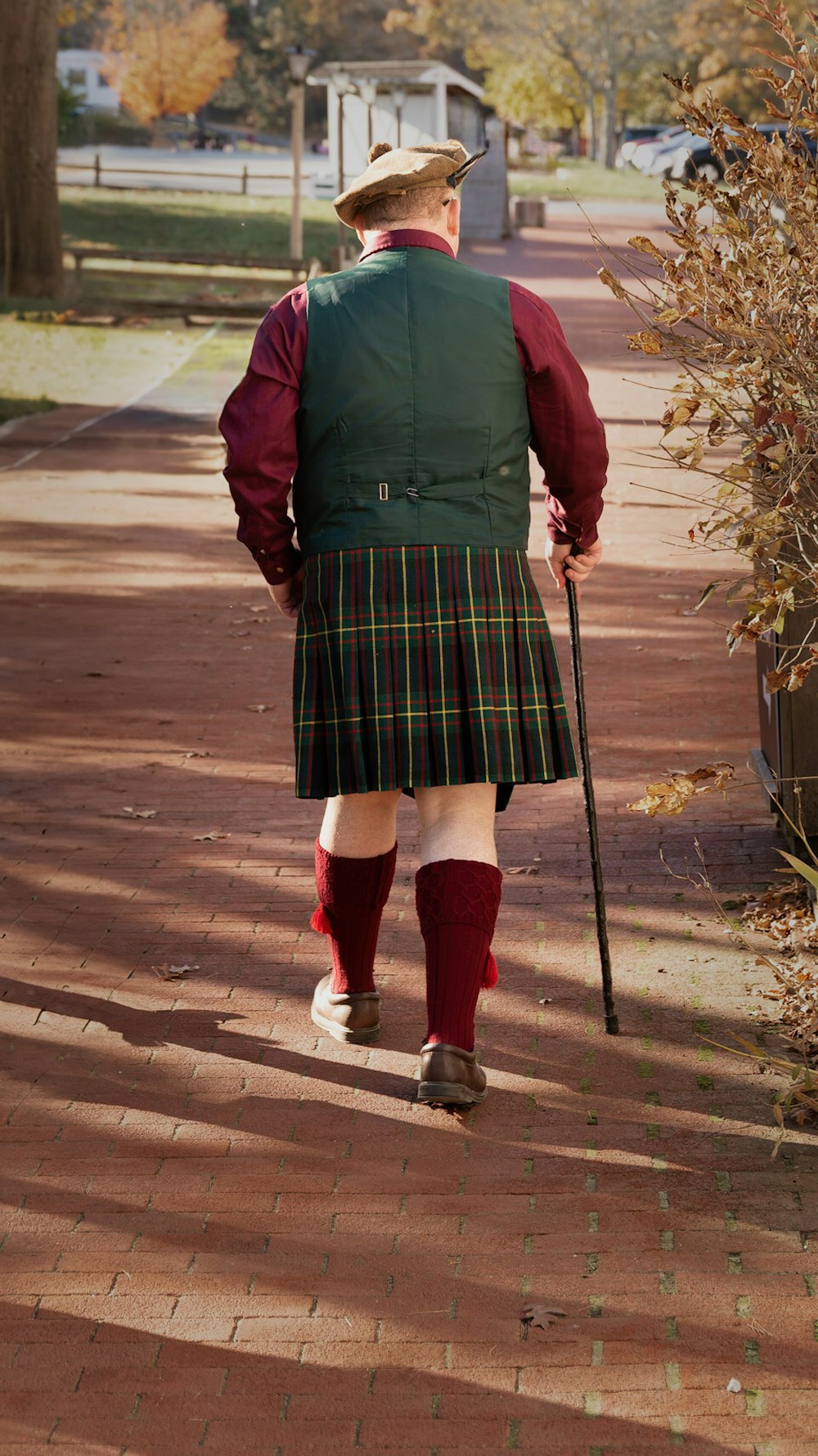 a man in a kilt walking down a sidewalk