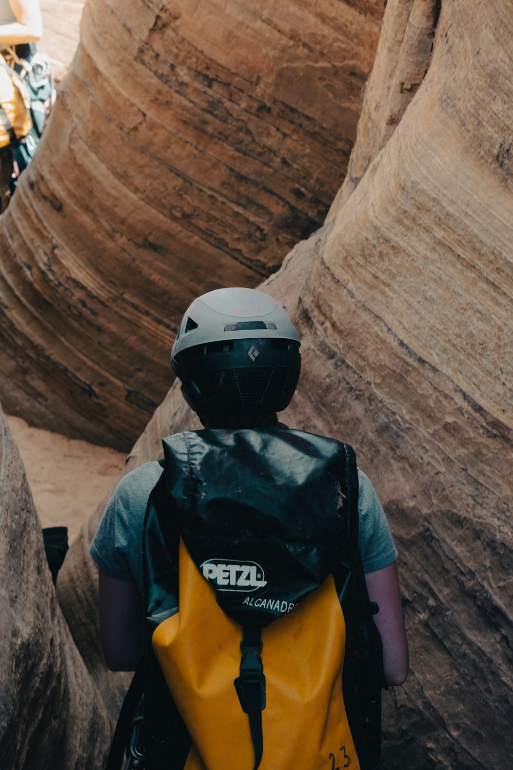 a person wearing a helmet and backpack walking through a canyon