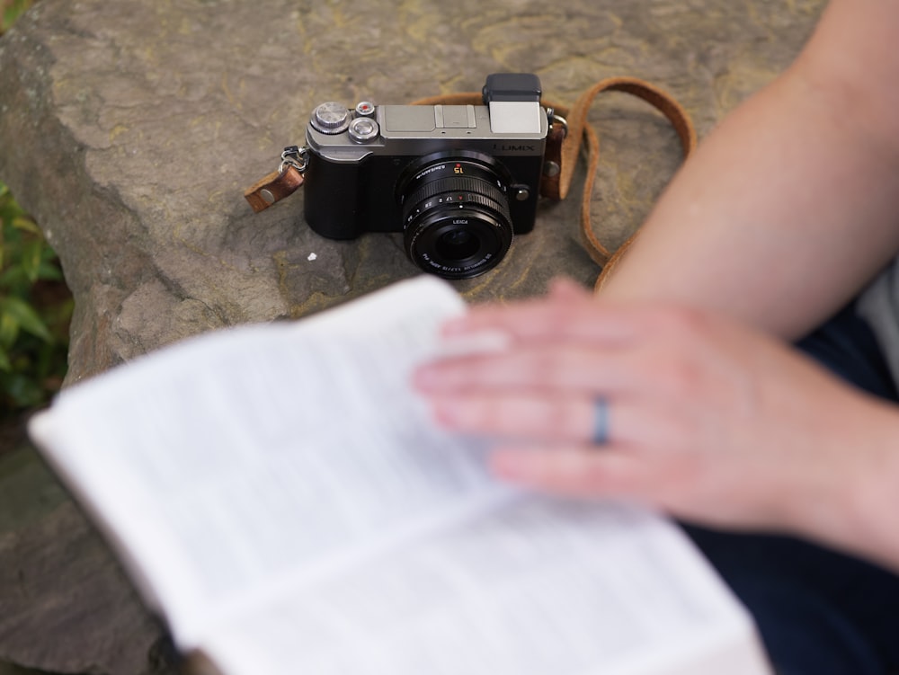 a person sitting on a rock with a book and a camera