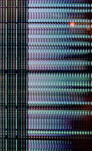 A close-up view of a digital display showing a grid pattern composed of tiny illuminated pixels. The arrangement includes vertical and horizontal lines forming a matrix with repeated patterns of light in vibrant colors.