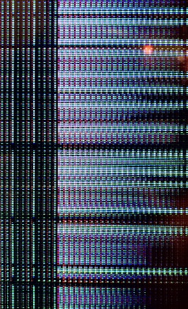 A close-up view of a digital display showing a grid pattern composed of tiny illuminated pixels. The arrangement includes vertical and horizontal lines forming a matrix with repeated patterns of light in vibrant colors.