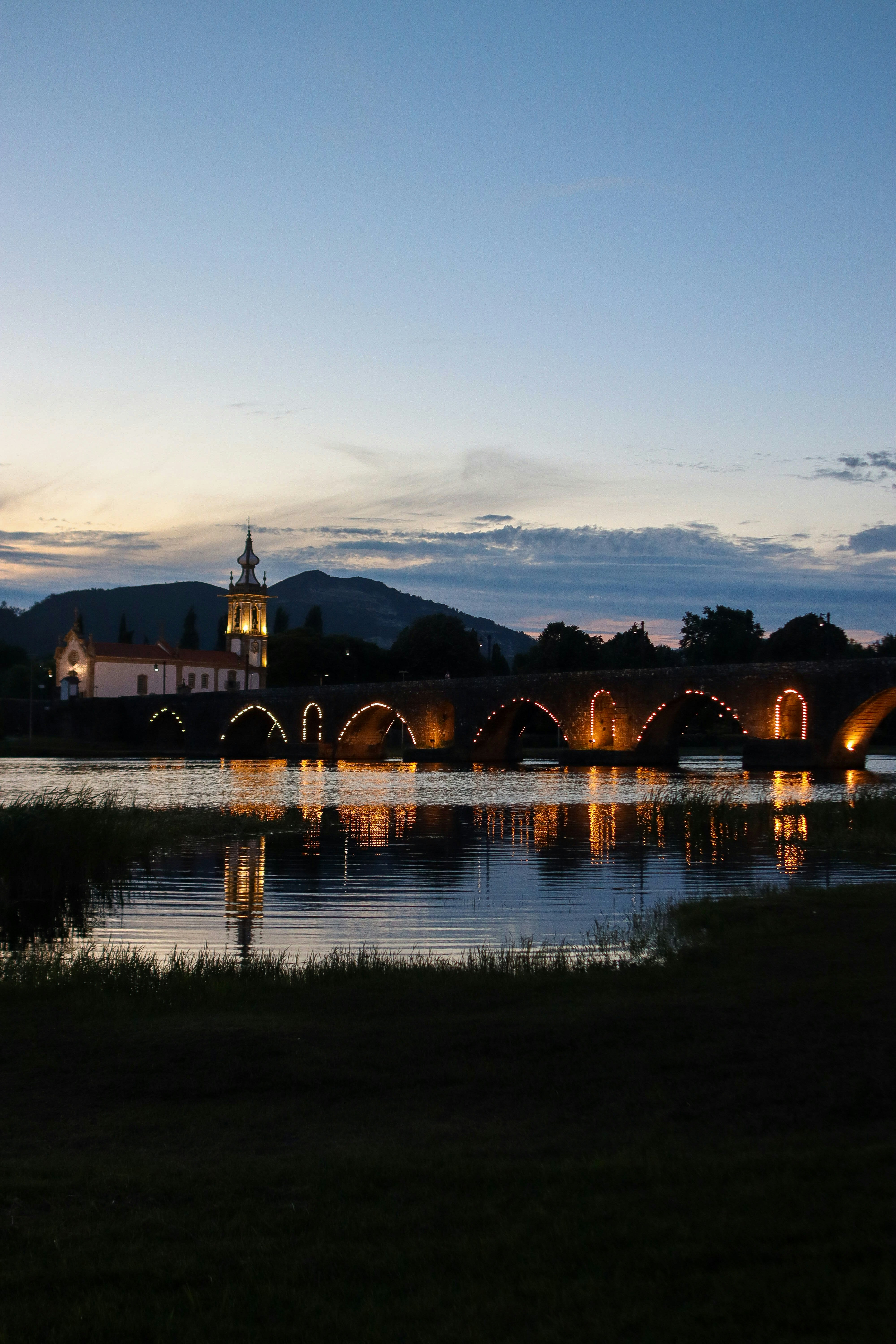 a bridge over a body of water with a clock tower in the background