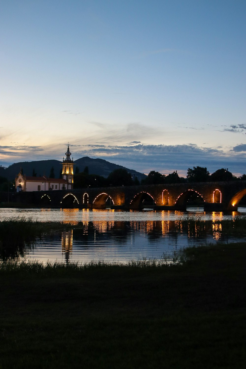 a bridge over a body of water with a clock tower in the background