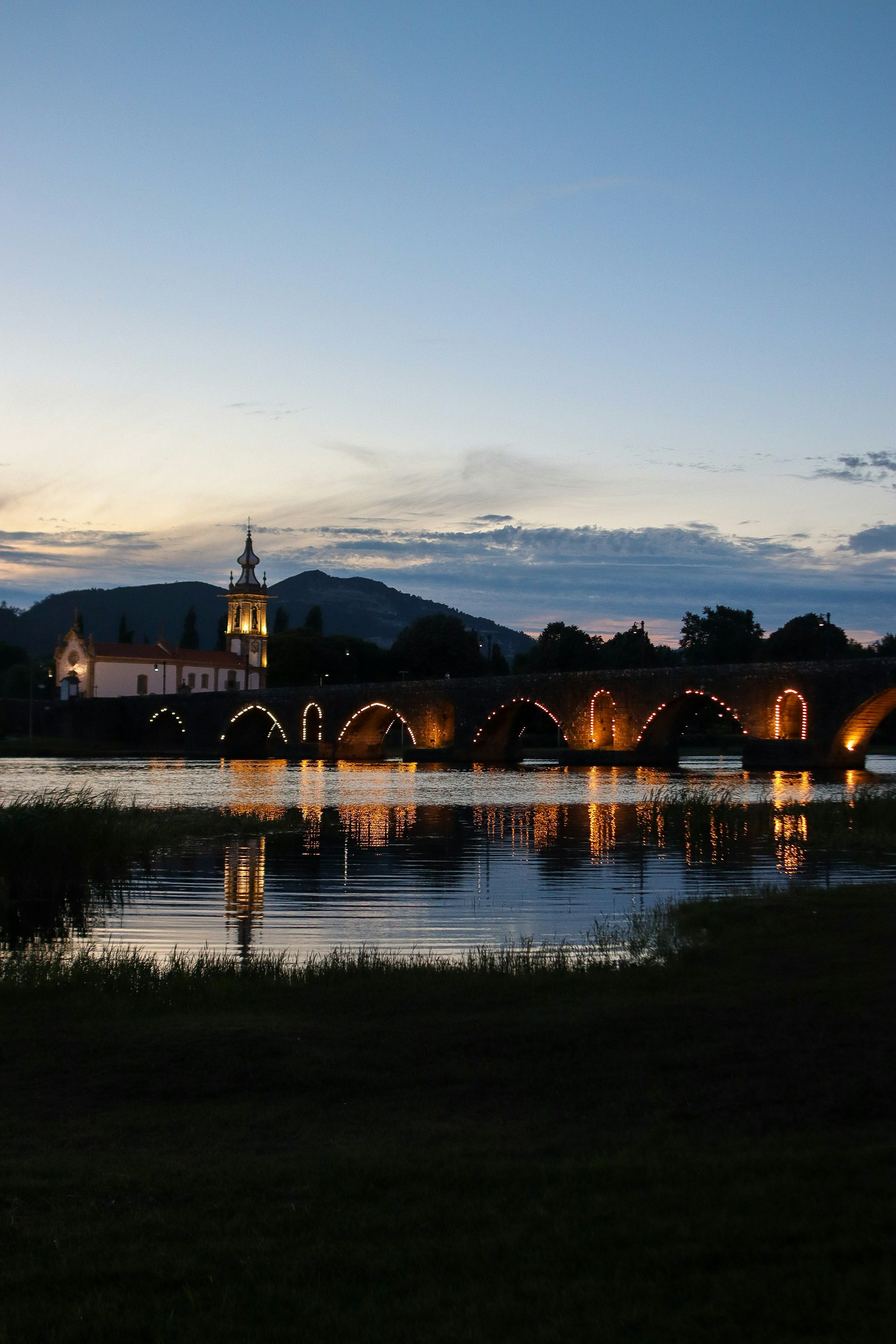 a bridge over a body of water with a clock tower in the background