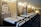 The interior of a showroom displaying several neatly arranged single beds lined up in a row. The beds have white mattresses and dark frames. Informative posters and samples are mounted on the walls, and there is a bright focus on a featured section at the end of the room labeled 'Royal Bed.'