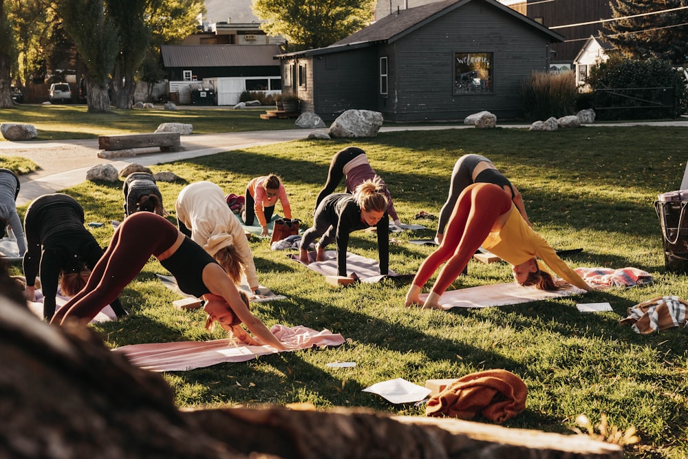 a group of people doing yoga in the grass