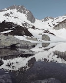 Snow-capped mountains towering above a serene alpine lake reflecting the peaks.