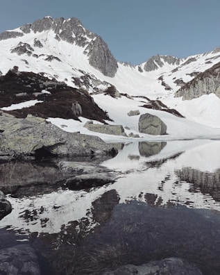 Snow-capped mountains towering above a serene alpine lake reflecting the peaks.