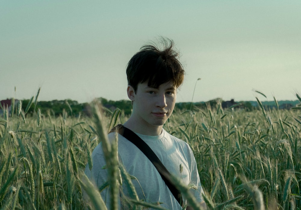 a young man standing in a field of tall grass