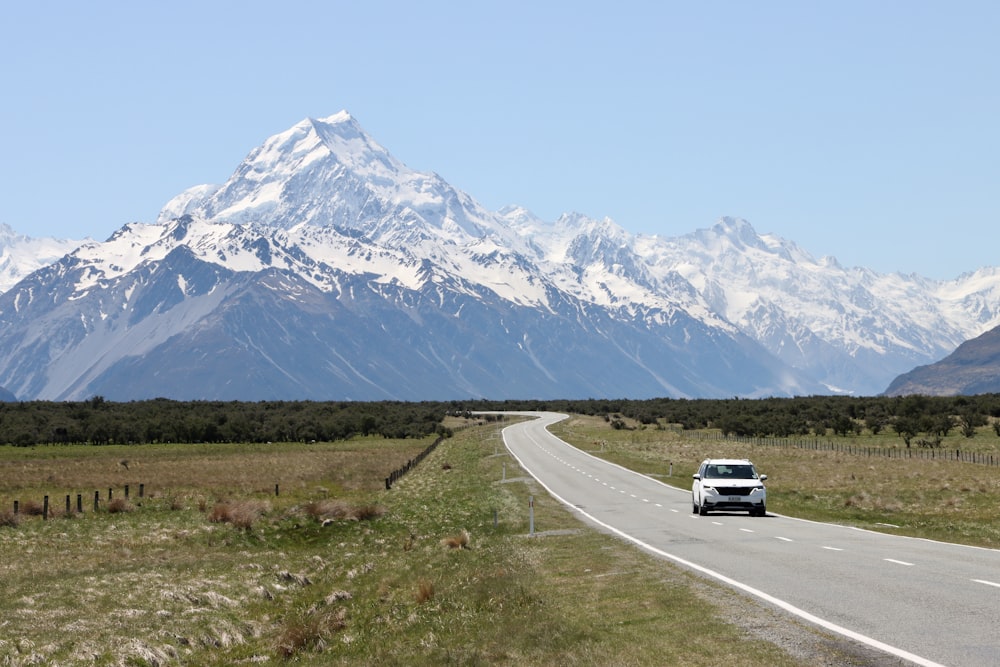 a car driving down a road with a mountain in the background