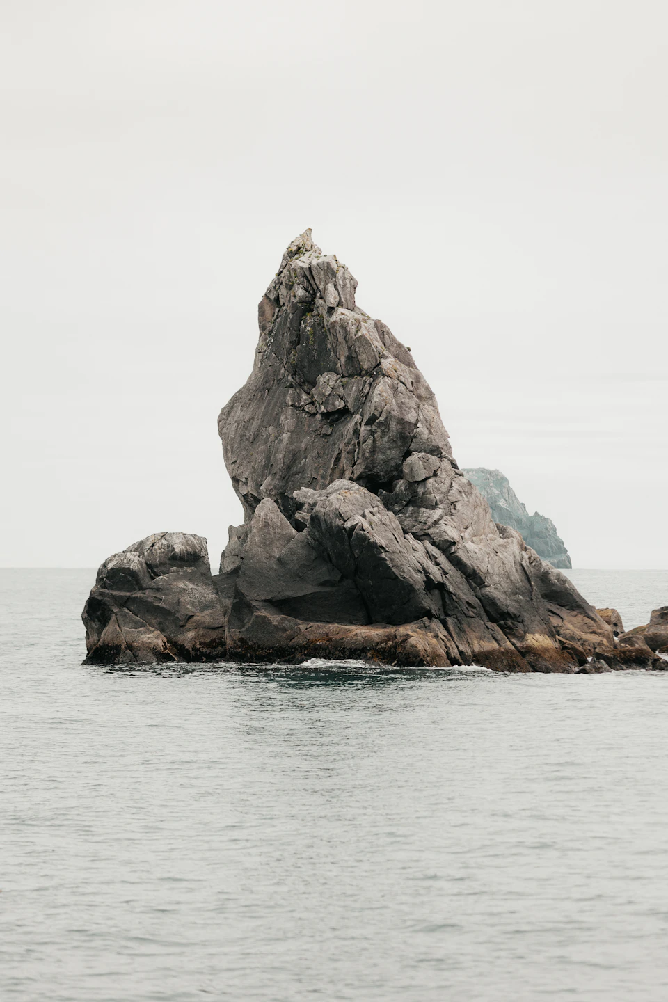 Two large gray boulders sit on rocky island shore, surrounded by vast ocean waters
