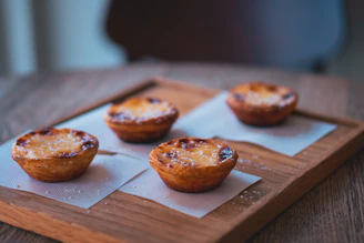 Close-up of golden, flaky Vietnamese pastries arranged on a rustic wooden board.