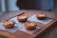 Four golden-brown pastries are neatly arranged on a wooden tray, each placed on a square napkin. The pastries have a slightly caramelized crust with scattered sugar crystals visible on their tops. The setting conveys a warm, cozy atmosphere with natural lighting gently highlighting the textures of the food and tray.