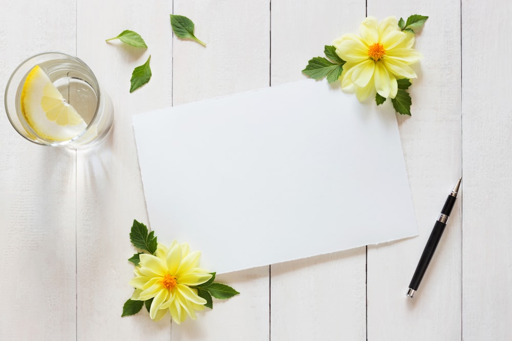 a blank paper with yellow flowers and a glass of water