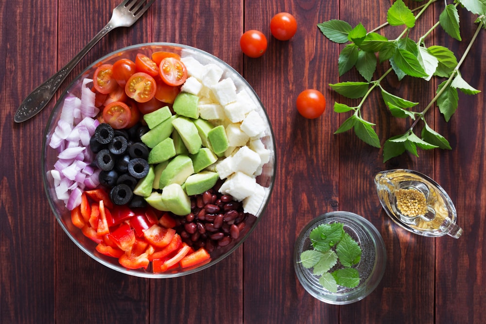 a bowl filled with vegetables and fruit on top of a wooden table