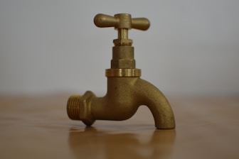 a brass faucet on a wooden table
