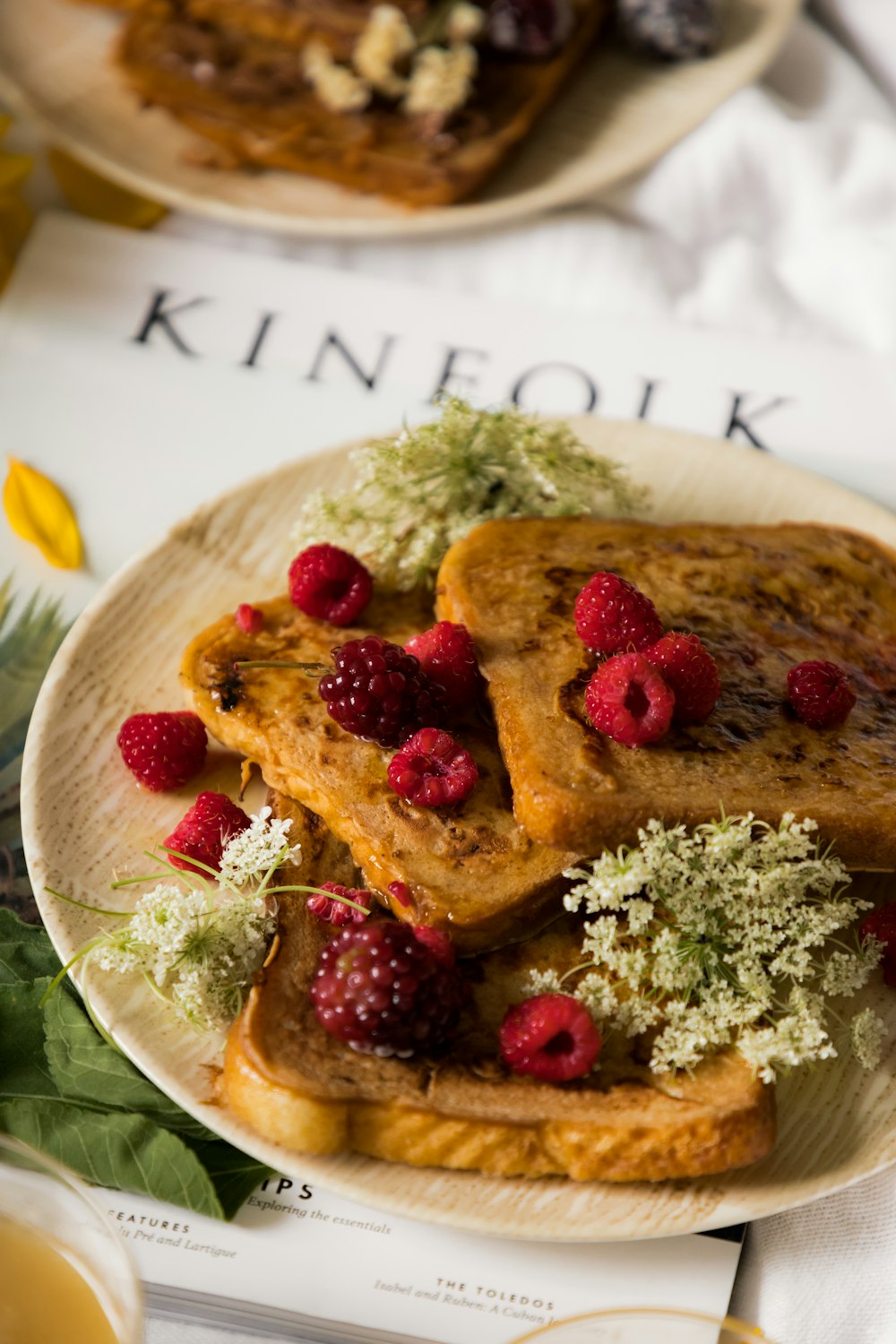 une assiette blanche garnie de pain perdu et de framboises