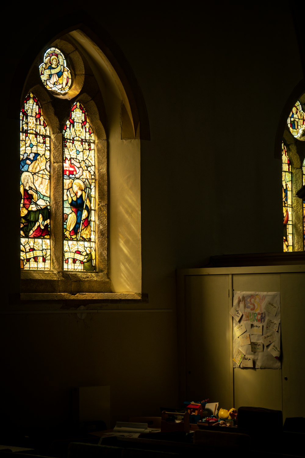 two stained glass windows in a dark room