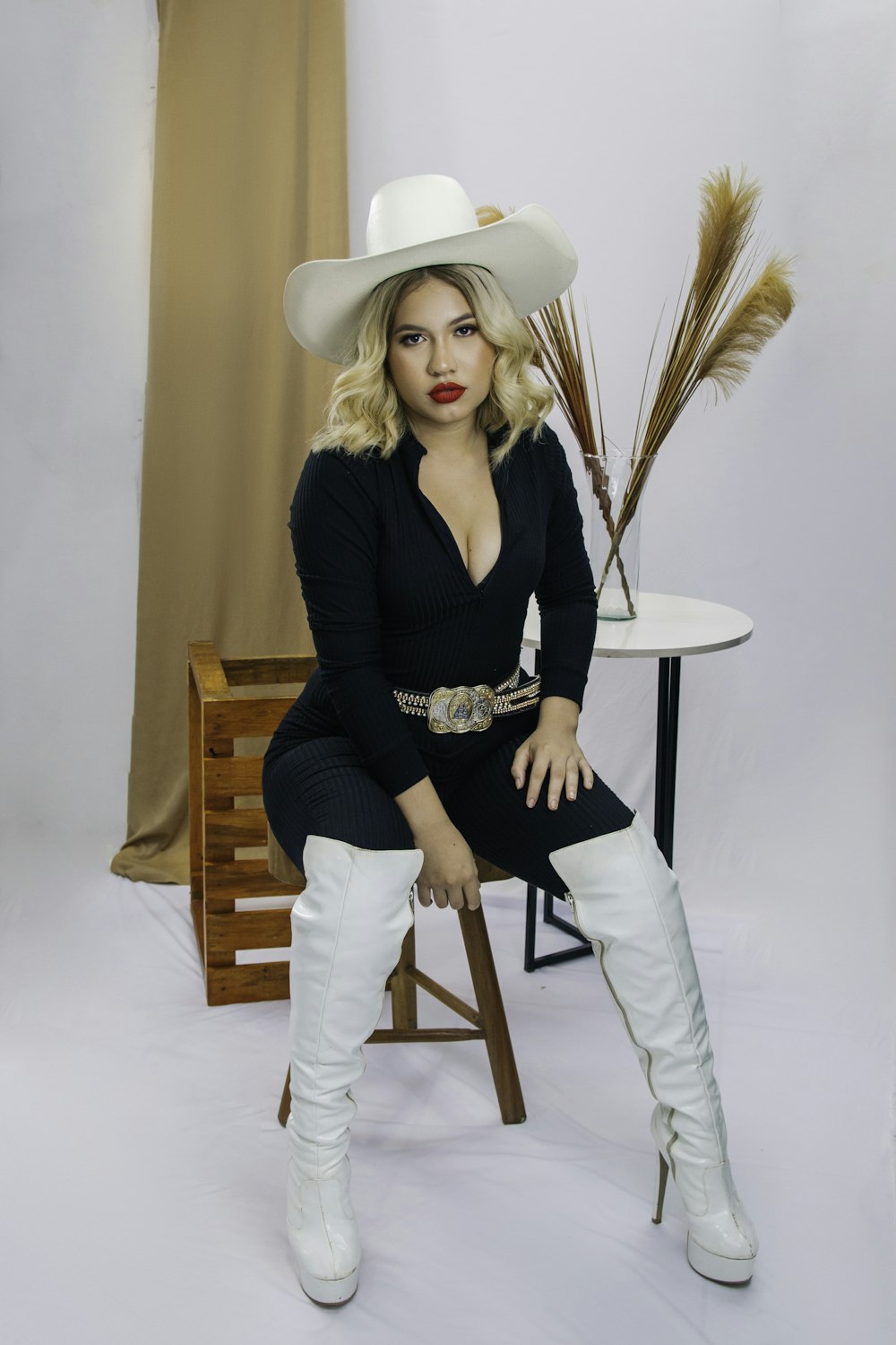 a woman sitting on a chair wearing a cowboy hat