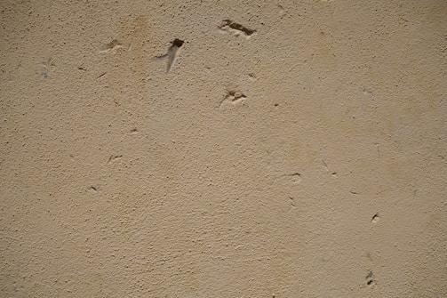A close-up of a handyman patching drywall with a putty knife.