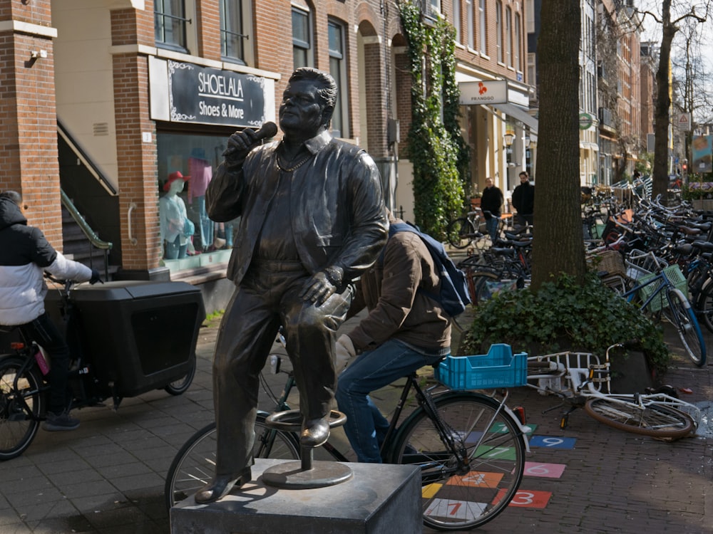 a statue of a man riding a bike on a sidewalk
