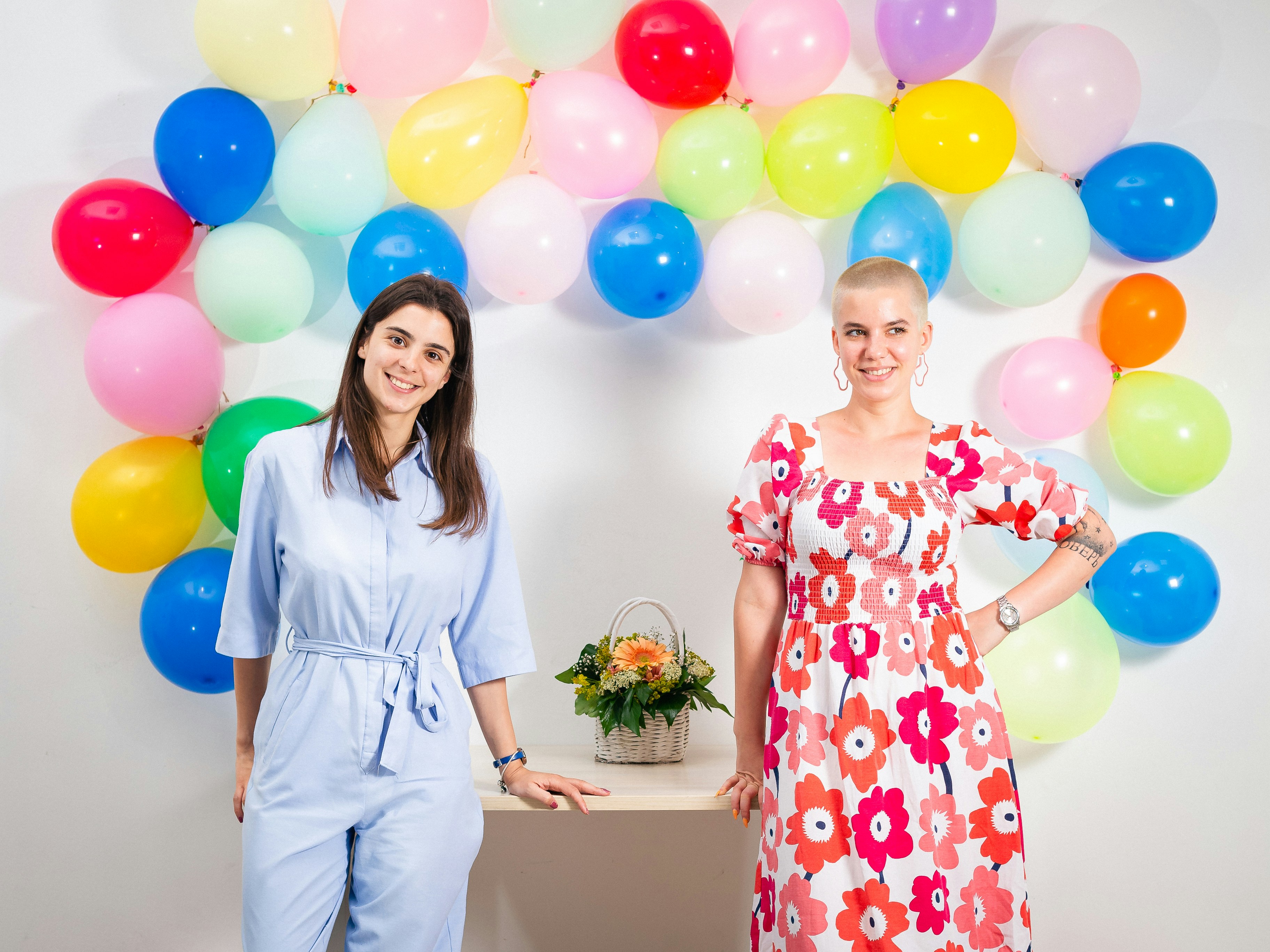 2 Women Coworkers standing in front of balloon decoration in Office