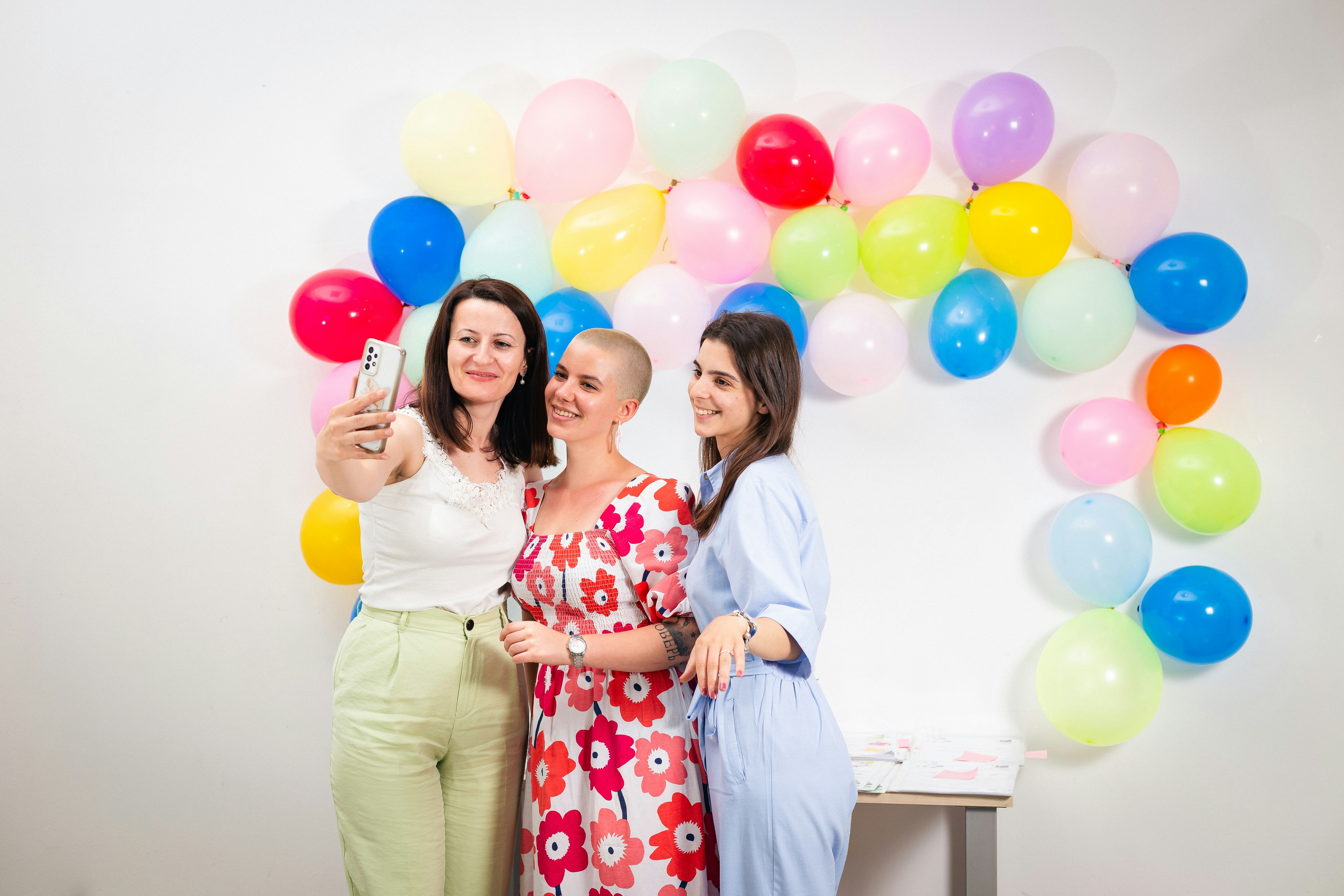 Three women smiling and taking a photo together to celebrate postpartum and new-mom milestones