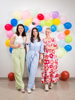 three women standing next to each other in front of balloons