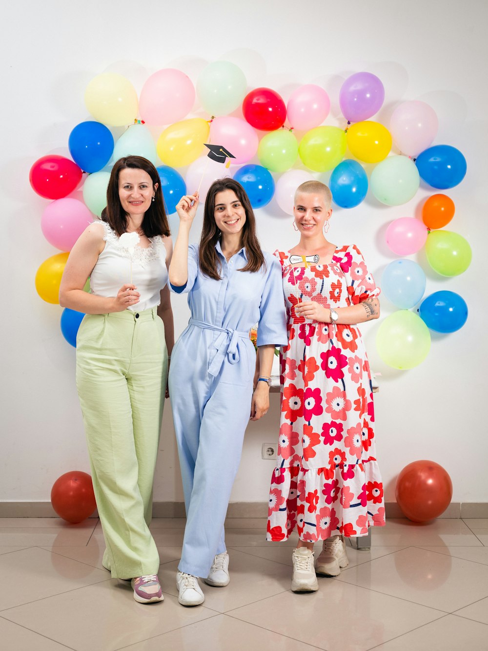 three women standing next to each other in front of balloons