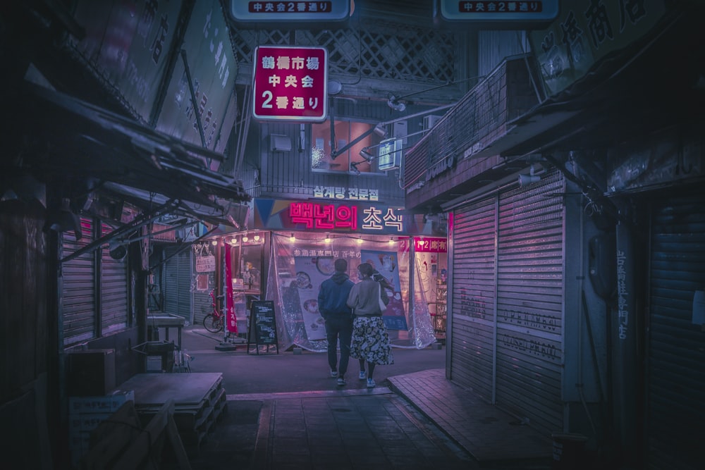 a couple of people walking down a street at night