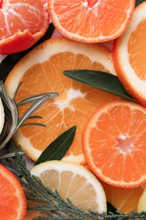 Sliced citrus fruits, including oranges and lemons, are artfully arranged with fresh leaves and herbs, creating a vibrant and refreshing display.