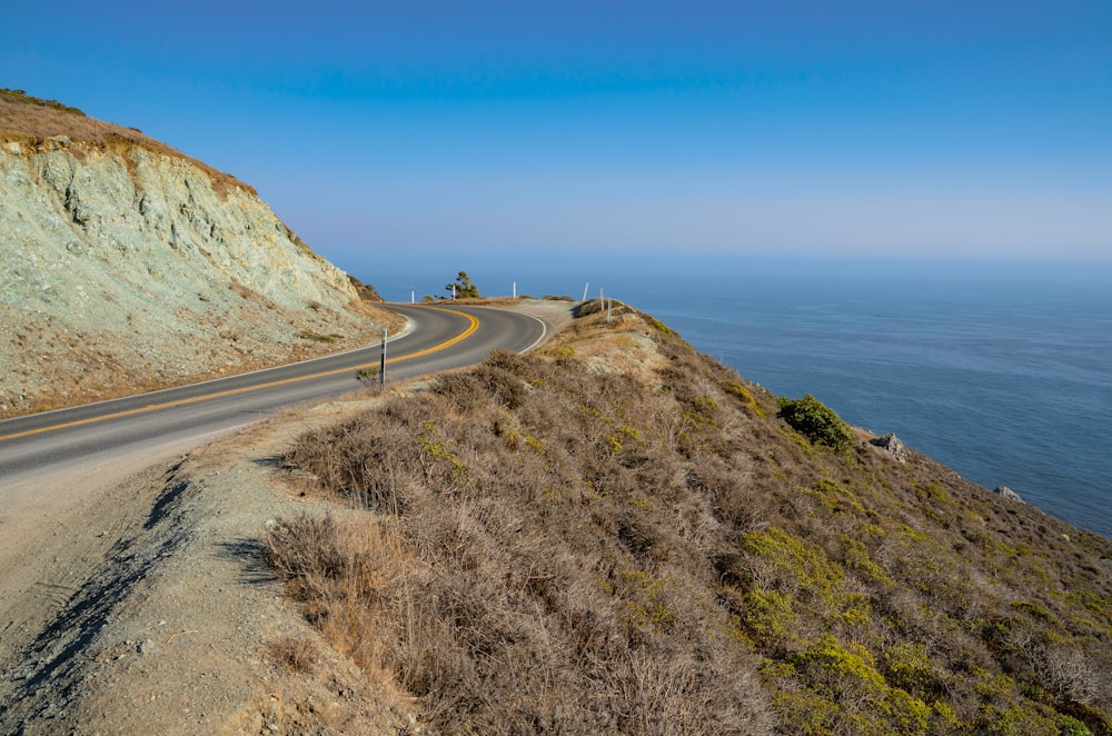 a curved road on the side of a cliff near the ocean