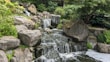 A cascading waterfall feature surrounded by natural stones and greenery.