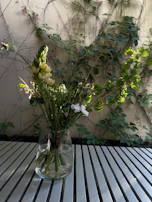 Elegant fiberglass vases in earthy tones holding fresh blooms on a garden bench.