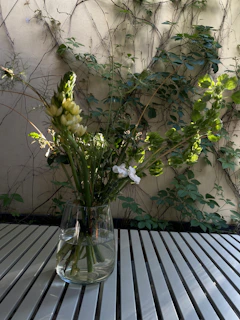 Elegant fiberglass vases in earthy tones holding fresh blooms on a garden bench.
