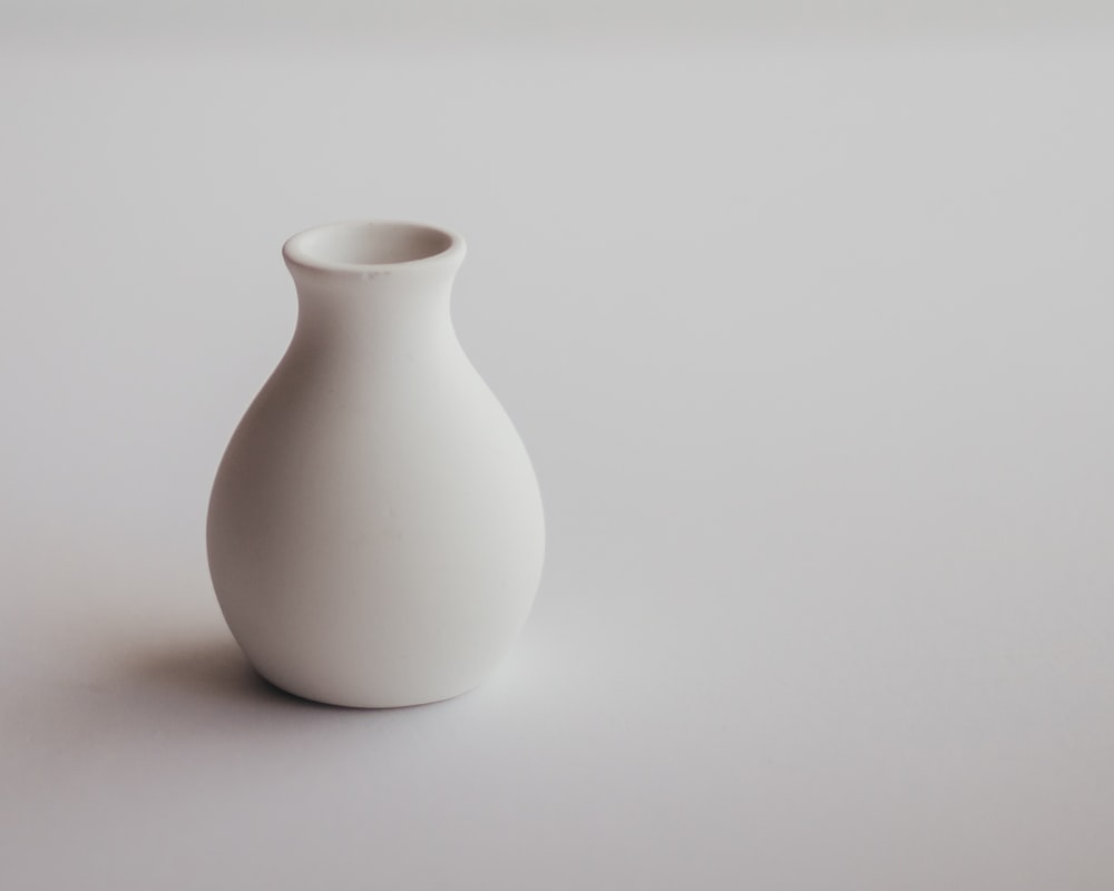 a white vase sitting on top of a white table