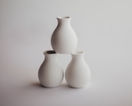 An elegant set of minimalist white ceramic vases arranged on a modern table.
