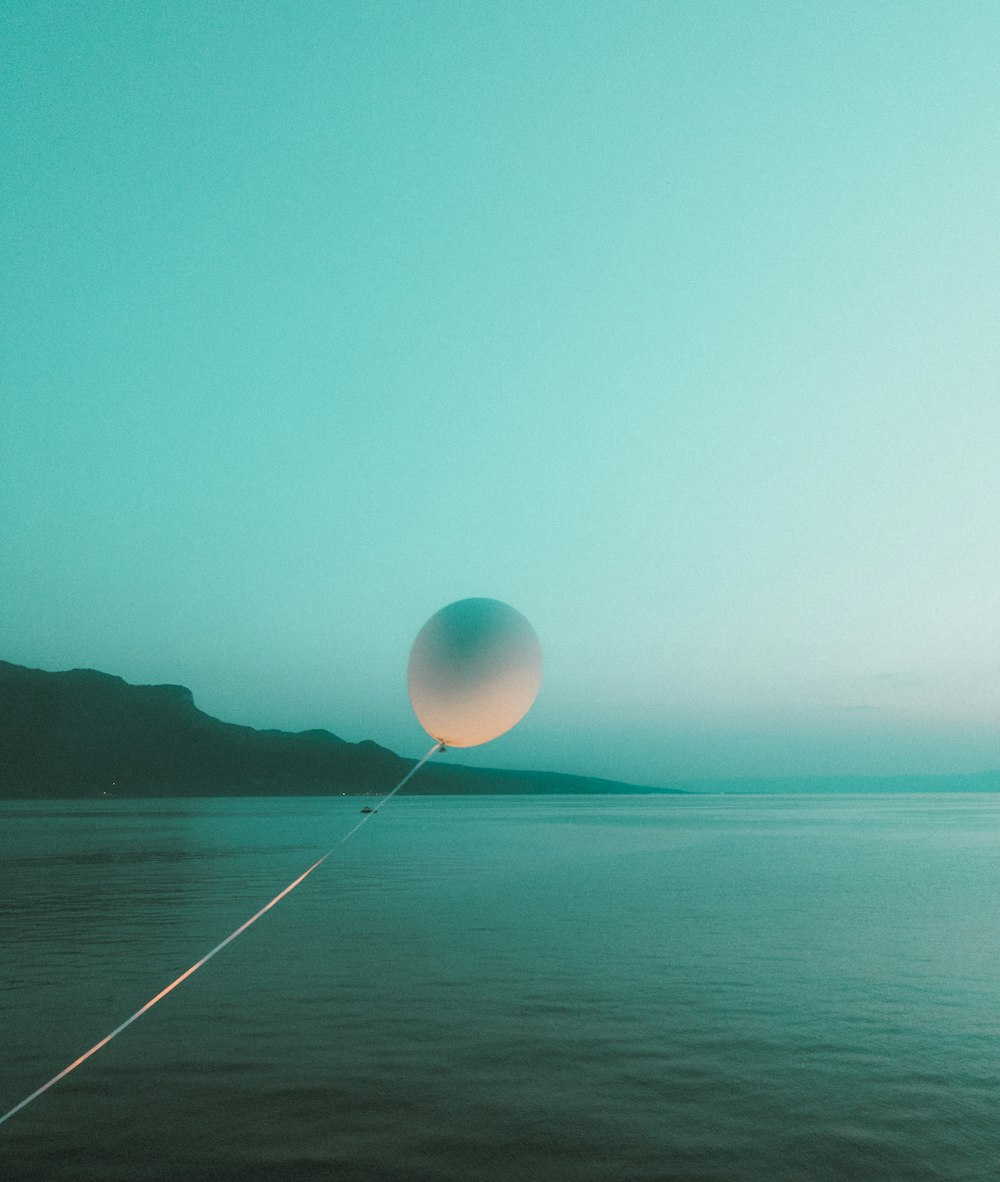 a balloon floating in the air over a body of water