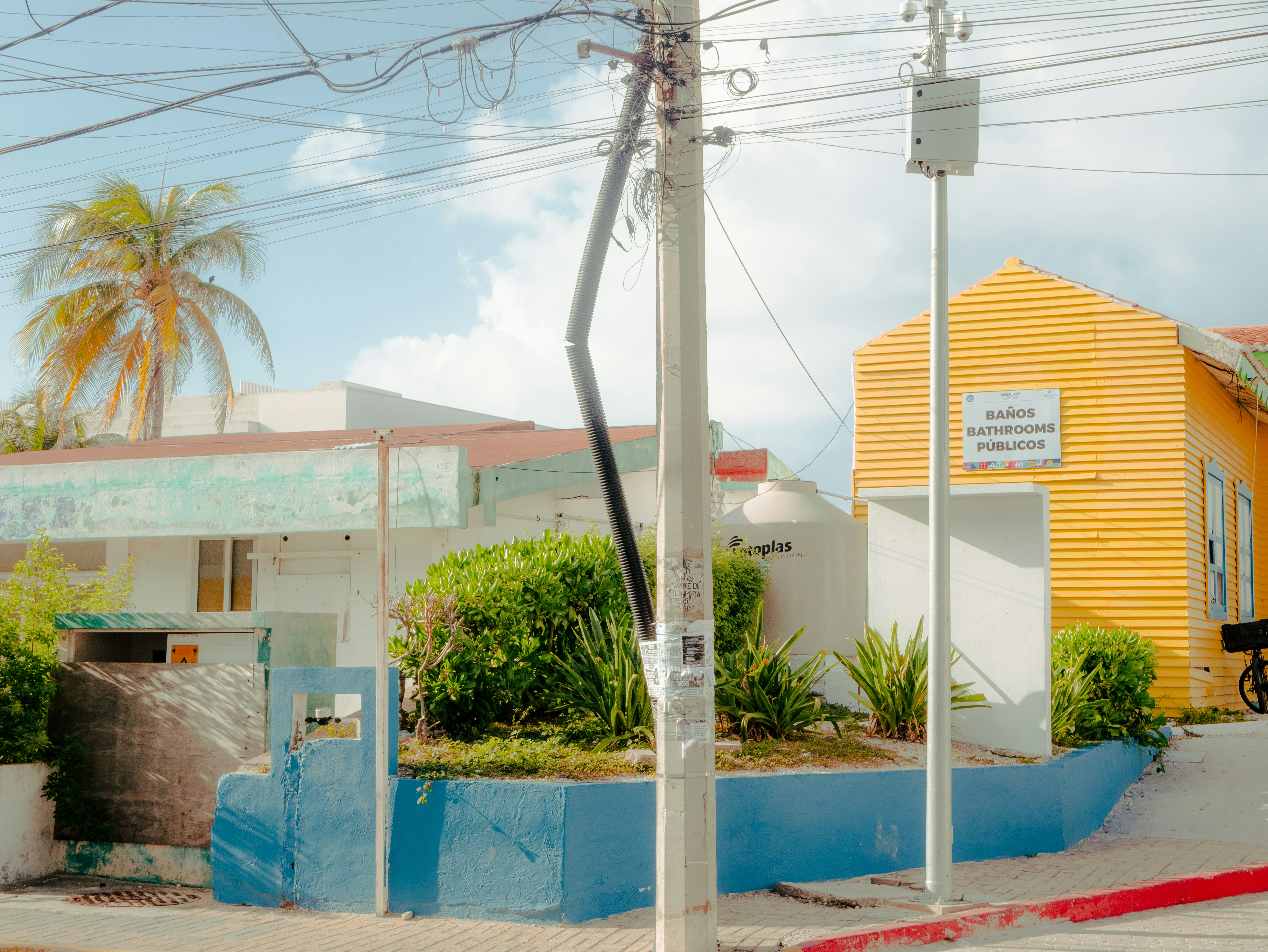 a yellow house with a blue wall and a red and white street sign