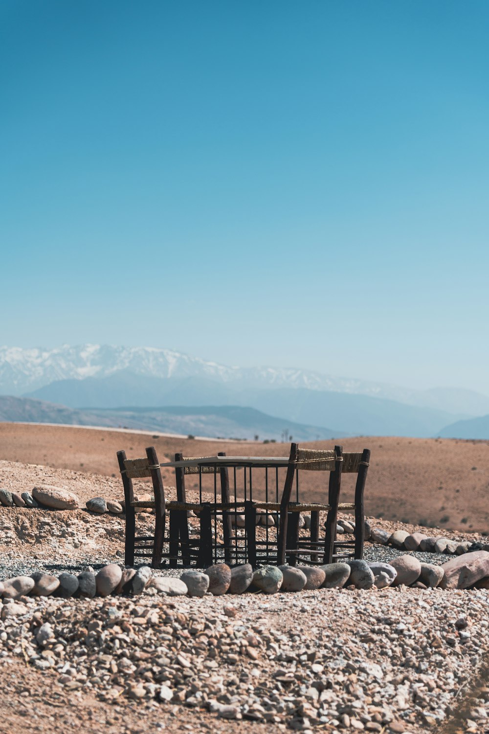 a wooden table and chairs sitting in the middle of a desert
